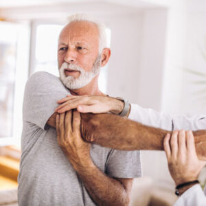 An image of a man with his arm over his chest at the chiropractor